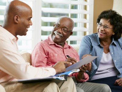 Financial Advisor Talking To Senior Couple At Home Smiling